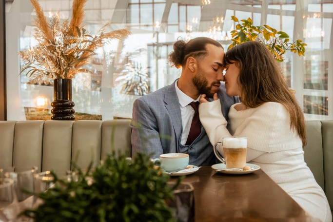 Couple Shooting Köln Café – Paar küsst sich voller Liebe im warmen Kaffeehauslicht © Chirlyart