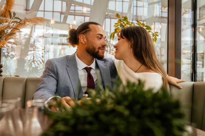 Couple Reportage Köln – Paar lacht natürlich im Café, Pflanzen im Hintergrund © Chirlyart