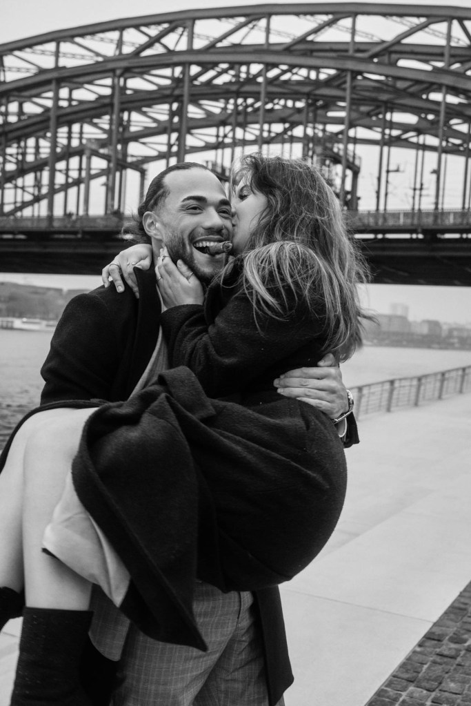 Paarfotografie Köln – Paar küsst und lacht auf der Brücke am Rhein, Herbst © Chirlyart