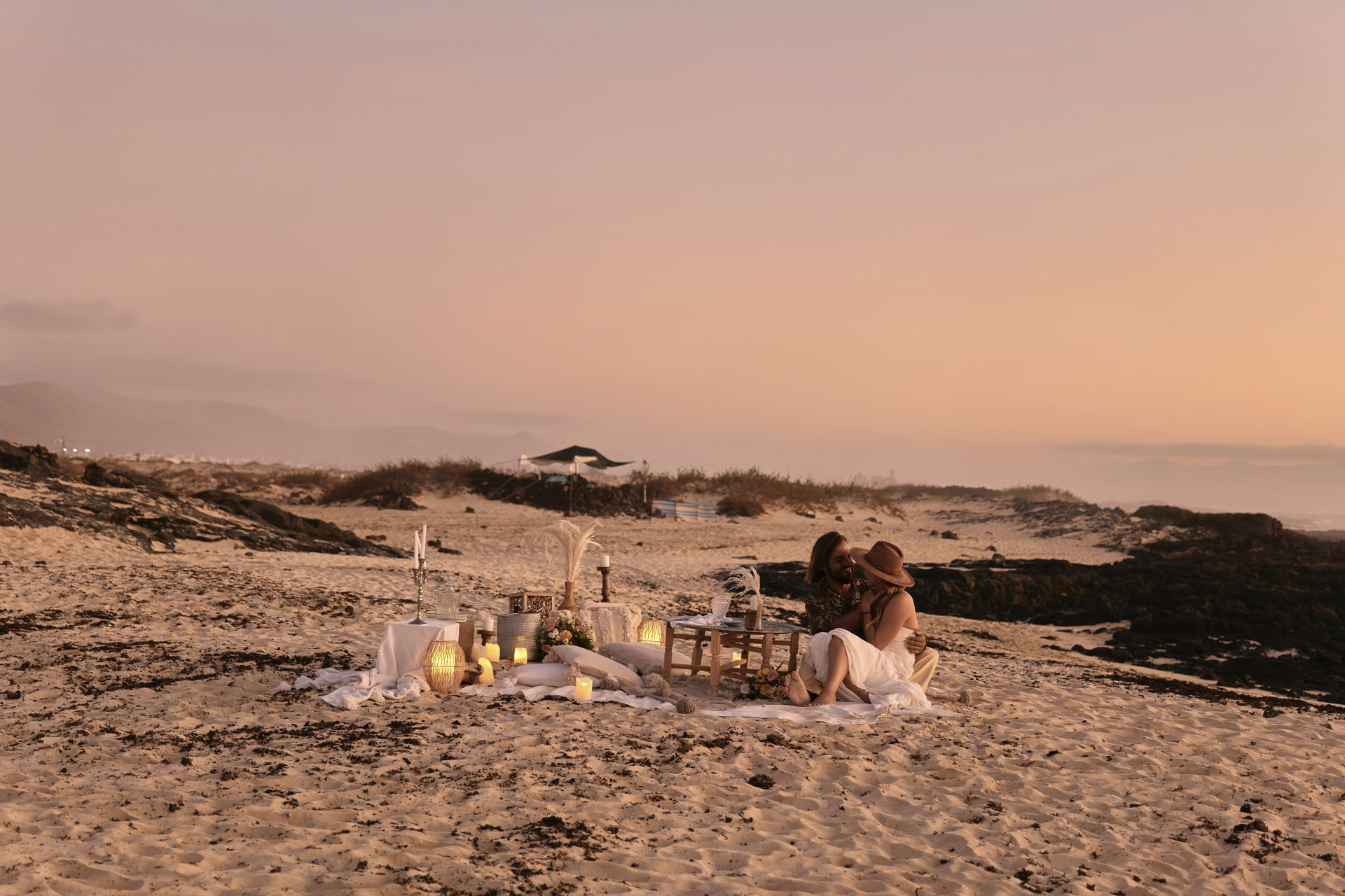 Elopement Fuerteventura – Dhana und Sascha Strand Zeremonie, Holztisch Kerzen Laternen goldene Stunde © Chirlyart