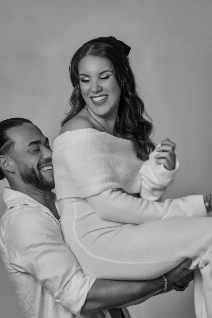 Paarfotografie Weihnachten – Paar lacht gemeinsam auf dem Stuhl, natürlicher Moment © Chirlyart