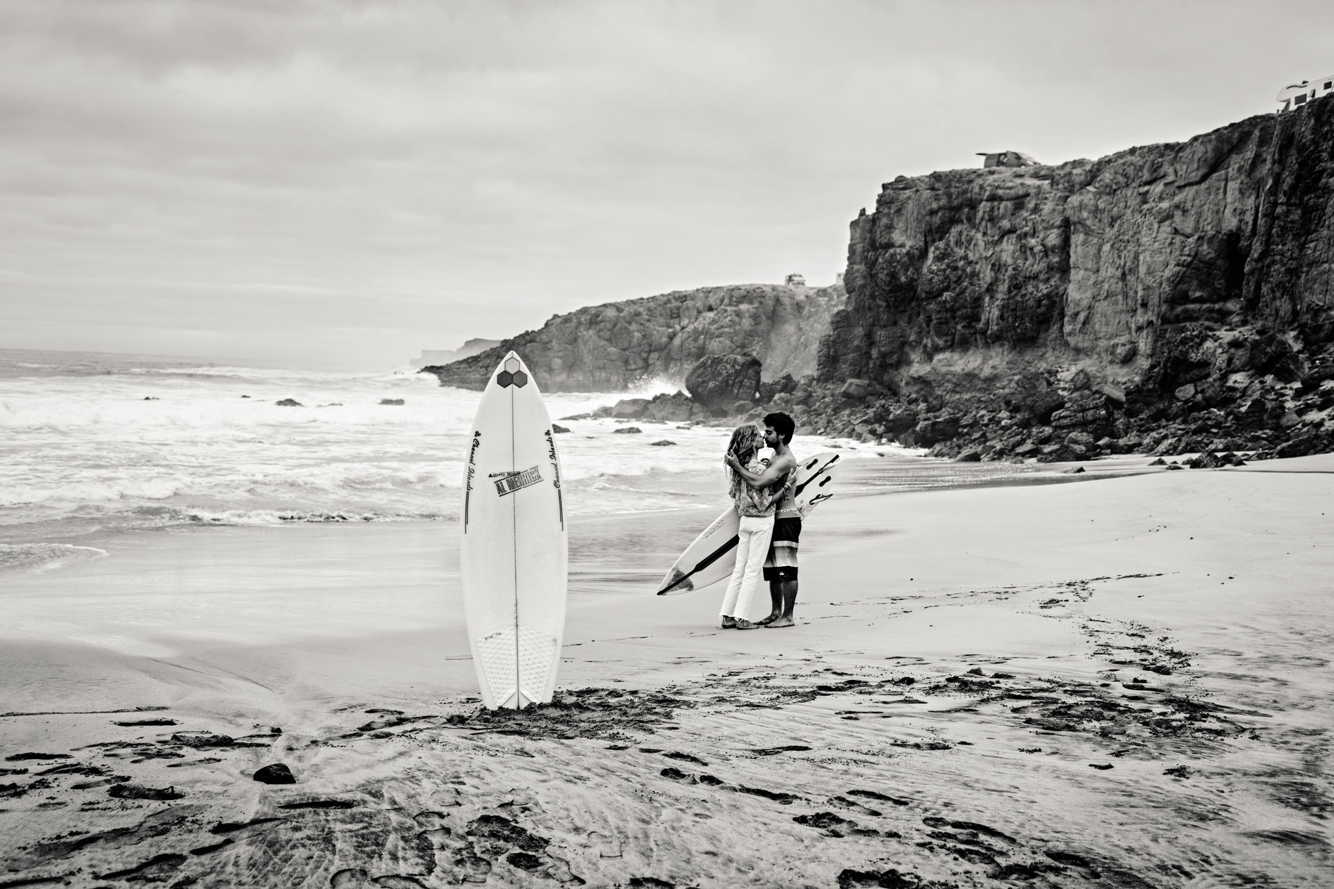 Surfing Love Story Fuerteventura – Paar mit Surfbrett am Atlantikstrand, dramatisches Licht Kanaren © Chirlyart