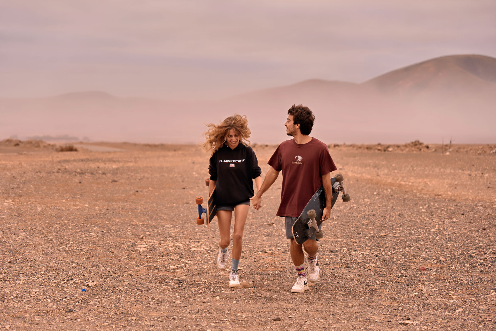 Ride and Romance Fuerteventura dramatisch – Paar auf Skateboards mit weiter Landschaft Kanaren, Abenteuer © Chirlyart