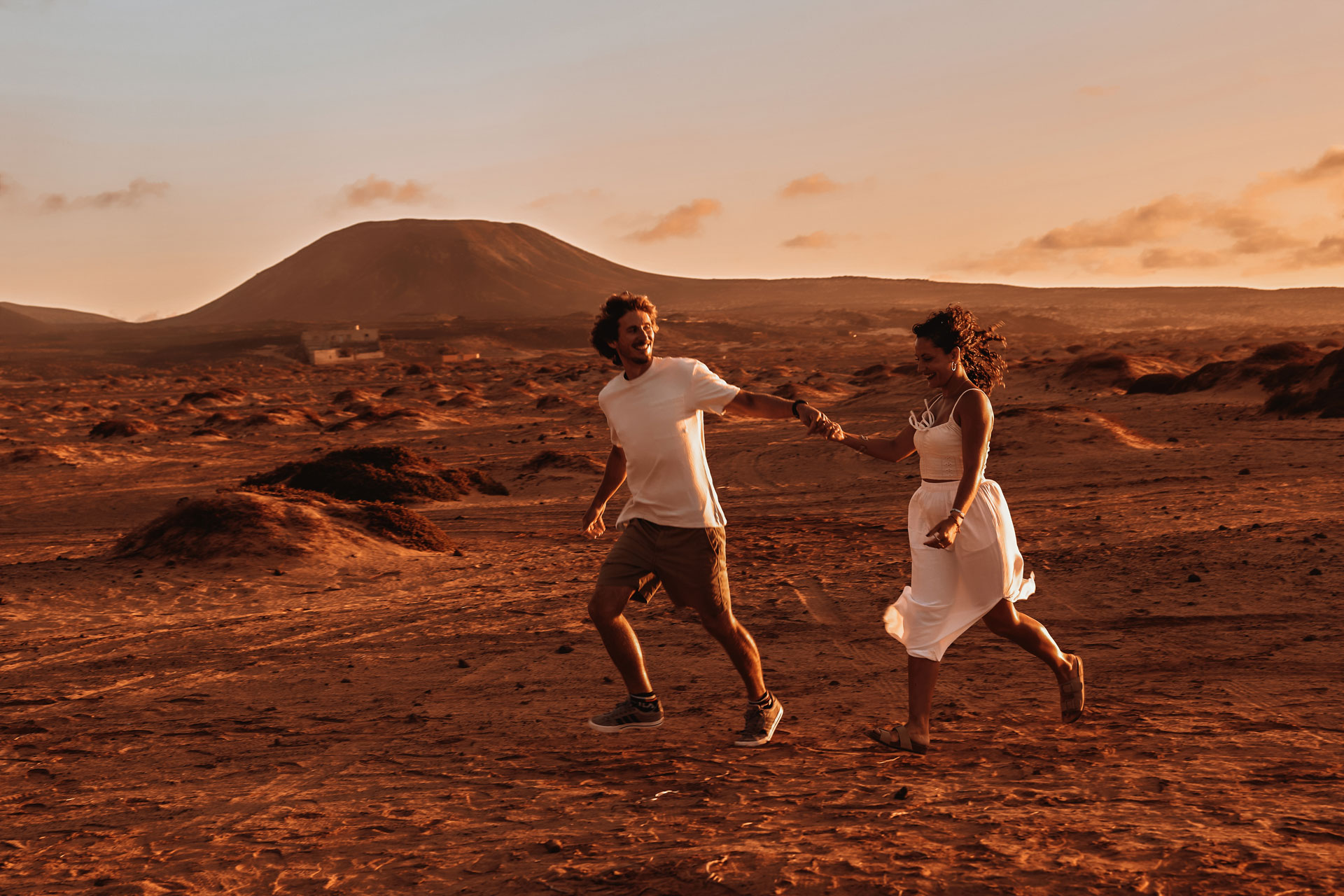 Paarshooting Dünen Fuerteventura – Paar tanzt spielerisch durch goldene Wüstendünen bei Abendsonne © Chirlyart